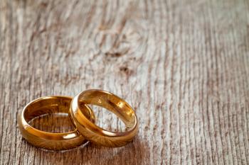Pair of golden wedding rings on wooden background