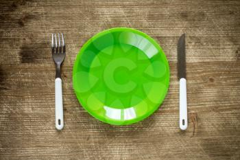 Empty plate, fork and knife on wooden background. Top view with text space