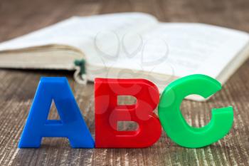 ABC spelling and open book on wooden background