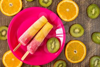 Popsicles with sliced fruits on dark wooden background. Summer food concept. 