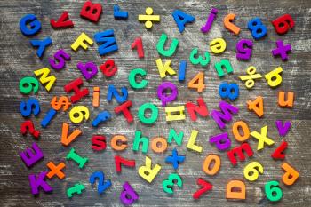 Background from colorful magnetic letters and numbers over a wooden background