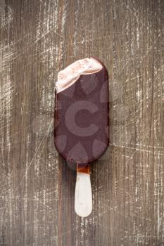 Bitten chocolate covered vanilla ice cream bar on a wooden stick