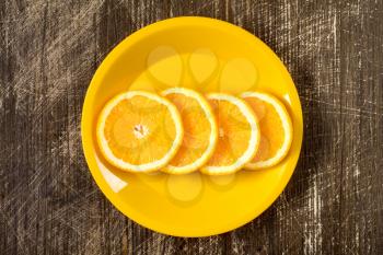 Orange slices in a yellow plate, top view