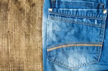 Neatly folded jeans on wooden background. Copy space.