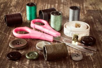 Tailor's tools - scissors, measuring tape,spools,buttons,etc. on wooden background
