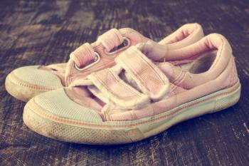 A pair of old pink sneakers on wooden background.Image has been filtered to give a retro or vintage style.