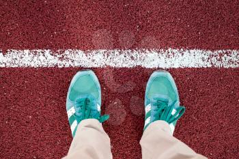 Feet are on the stadium track with a white stripe