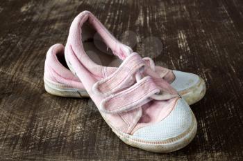  A pair of old pink sneakers on wooden background. Close up.