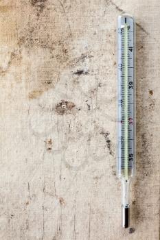 Clinical thermometer on old canvas background.Copy-space.