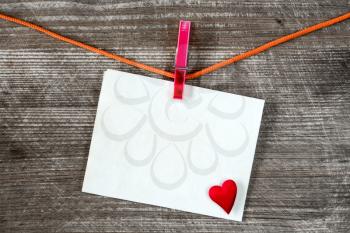 Message and red heart on the clothesline against wooden background