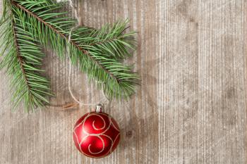 Wooden background with fir branch and red christmas bauble. Copy-space.