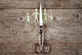 Scissors and paper family on wooden background. Broken family or divorce concept.