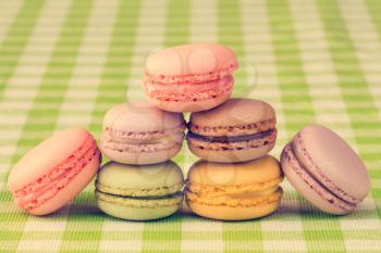  French delicious dessert macaroons stacked on checkered tablecloth, vintage tone