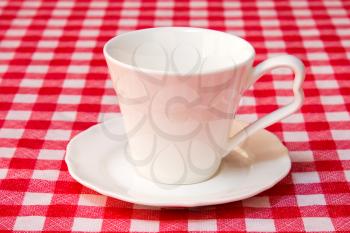 White cup on the checkered tablecloth texture