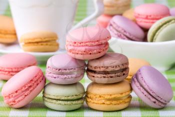 Delicious french macaroons with cup of coffee on background