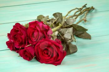 Bouquet of red roses on blue wooden surface