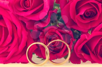 Wedding rings with red roses on background