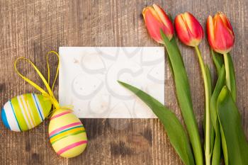 Easter eggs,spring tulips and blank card for copy-space