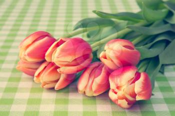 Bouquet of spring tulips on table with checkered tablecloth