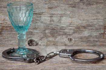 Glass with handcuffs as symbol for alcohol abuse