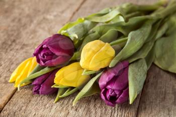 Bouquet of yellow and purple tulips lying on wooden background