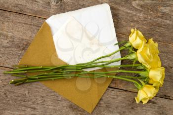 Yellow roses and love letter or note card with golden envelope