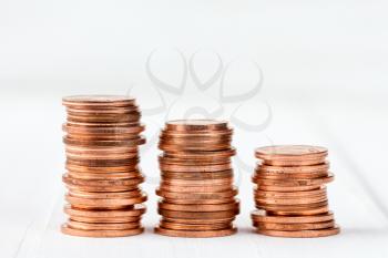 Three stacks of copper coins on white wooden background