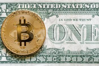 Golden bitcoin coin on us dollar close up