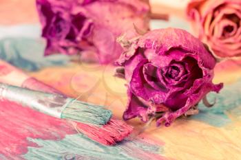 Abstract painting with dried roses and paint brushes