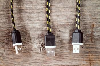 Three USB cables hanging over wooden background