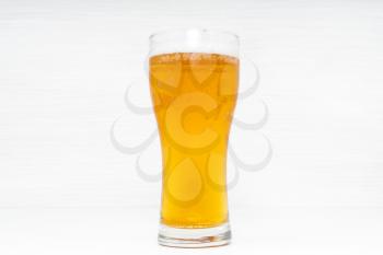 Glass of light beer on white wooden background