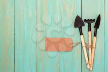 Gardening tools with blank tag on wood background