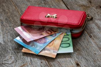Red female wallet full of euro cash money banknotes