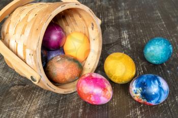 Painted Easter eggs basket on wooden background