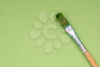 Dirty paint brush on green paper background.Copy space.