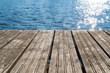 Empty  wooden platform with sea background and sunlight reflecting in water