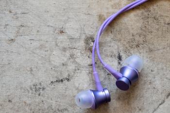 Purple earphones on grunge background, close-up view
