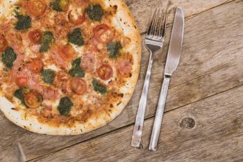 Delicious pizza on dark wooden background with fork and knife