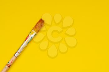 Dirty paint brush on yellow paper background.Copy space.