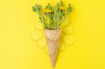 Flowers in a waffle cone on a yellow background. Flat lay, top view.