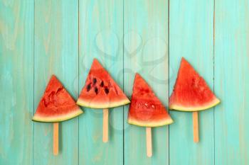 Watermelon slice popsicles on a blue wood background