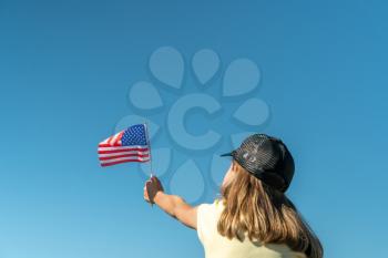 Girl holds an American flag on a sky background