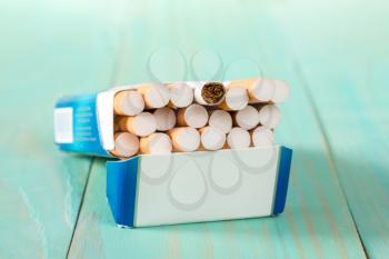 Open pack of cigarettes lying on a blue wooden background