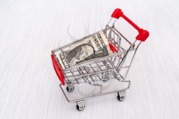 Shopping cart with one dollar. Money market concept.