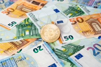 Gold Bitcoin coin on bills of euro banknotes. Worldwide virtual internet cryptocurrency and digital payment system