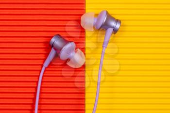 Purple audio earphones on the colorful paper background
