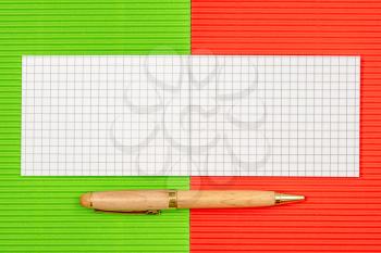 Small notebook with a pen on the colorful paper background. Copy-space.