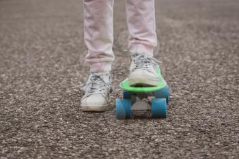 Close-up of skateboarder legs. Girl ride skateboard on a city street