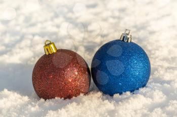 Blue and red Christmas baubles on the white fresh snow