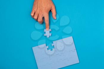  Concept of business, finding solution. Businessman solving puzzle on blue background.